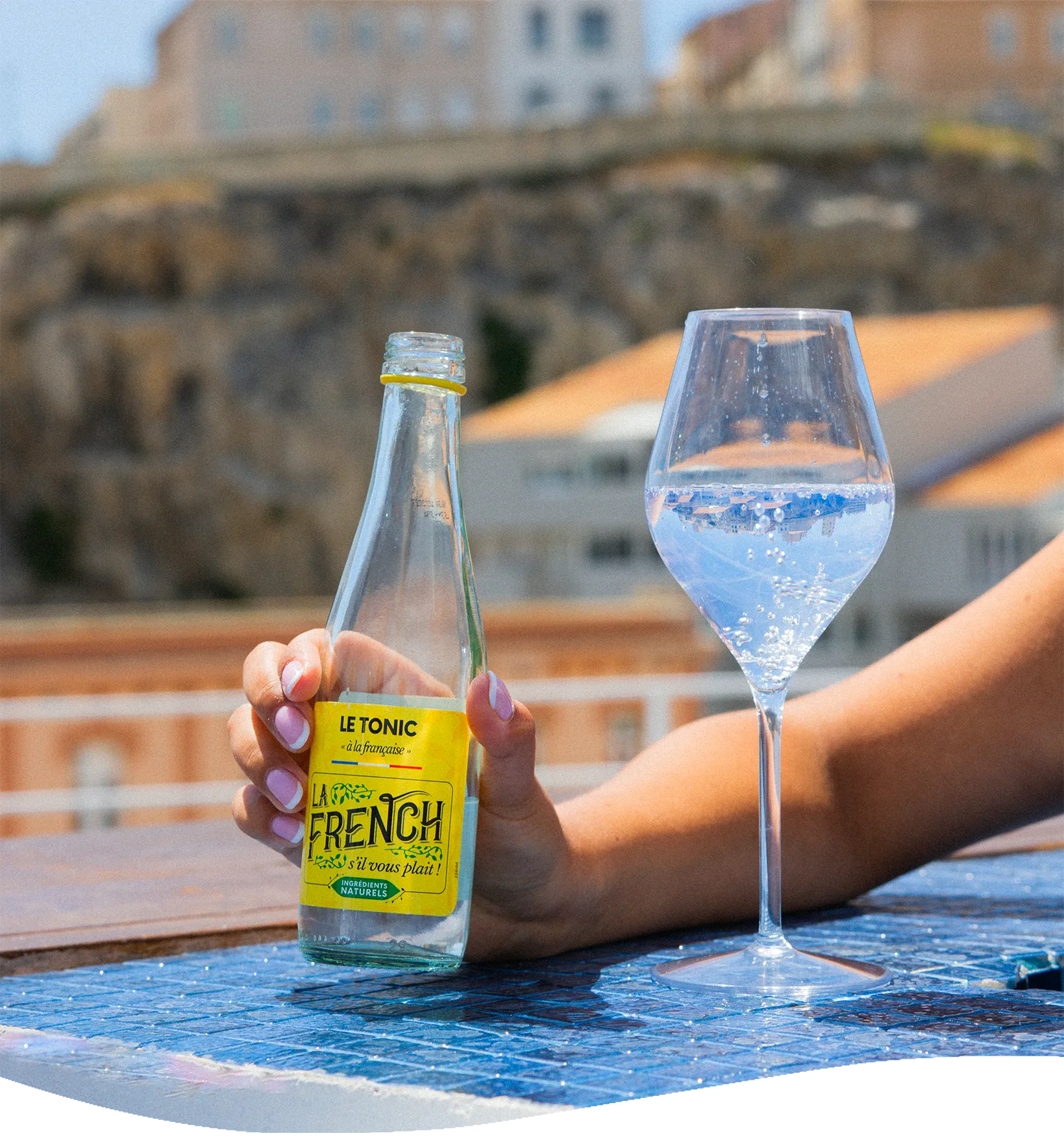 Main tenant une bouteille Le Tonic à la française et un verre pétillant